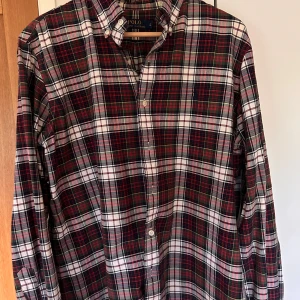 Rutig skjorta från Polo Ralph Lauren - Klassisk rutig skjorta från Polo Ralph Lauren i färgerna röd, grön, vit och svart. Skjortan har knappar hela vägen, button-down krage och lång ärm. Perfekt för dig som gillar tidlös stil med en preppy touch. Helt oanvänd skjorta.                            Ny pris 1 299, pris kan diskuteras 