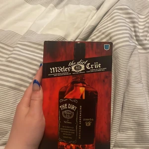 The Dirt: Mötley Crüe - Säljer boken 'The Dirt' av Mötley Crüe. En biografi om världens mest ökända rockband, fylld med galna historier, bilder och insikter om bandets livsstil. Omslaget är rött och svart med en bild på en whiskyflaska och bandets logga. Perfekt för rockälskare och fans av Mötley Crüe. Köpt second hand och därav sämre skick.