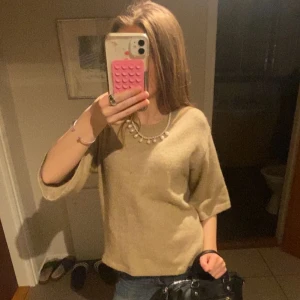 Beige stickad tröja med halvlånga ärmar - Mysig beige stickad tröja med halvlånga ärmar och avslappnad passform. Perfekt att styla med jeans eller kjol för en enkel och stilren look.
