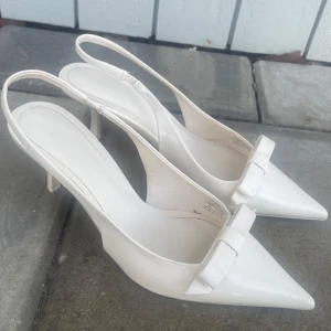 Cremevita klackskor med rosett - Cremevita klackskor från Zara med rosett vid tån. Endast använda 1 gång på balen därav mycket bra skick. Storlek 39. Superfina nu till sommaren🤍 nypris: 399kr