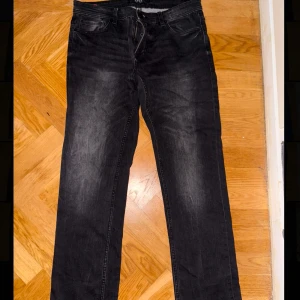 Svarta jeansbyxor med raka ben - Säljer ett par svarta jeansbyxor med raka ben och klassisk femficksdesign. Jeansen har en lätt tvättad look och normal passform. Perfekta för en avslappnad stil.