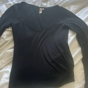 Svart långärmad topp från Nelly  - Svart långärmad topp från nelly med v-ringad halsringning och diskret . Säljer pga att den inte kommer till användning. Använd ca 4 ggr. Köpt för 200kr säljer för 120kr. Inga hål eller märken på sig. För mer frågor eller bilder skriv privat