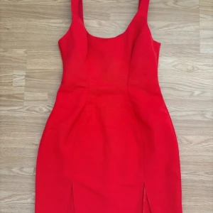 Röd tight klänning med slits - En figursydd röd klänning från asos design. Jättefin och aldrig använd då den var för liten. En tråd är lös men det syns knappt (se bild 4)