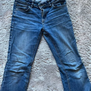 Blå jeansbyxor från Lindex - Säljer ett par klassiska blå jeans från Lindex i modell Freja. Byxorna har normal passform, fem fickor och dragkedja med knapp. Perfekta till vardags för dig som gillar en tidlös stil.