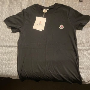 T-shirt  - Säljer en svart t-shirt med klassisk rund hals och broderad logotyp på bröstet. T-shirten är i mjuk bomull och har en enkel, stilren design. Perfekt för dig som gillar exklusiva märken och minimalistisk stil. Tröjan är helt ny, aldrig blivit använd. Priset kan diskuteras☺️
