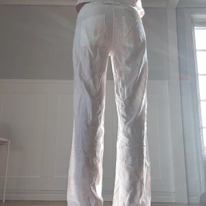 Vita linnebyxor med dragsko - Säljer ett par vita linnebyxor med rak passform och resår i midjan samt dragsko. Byxorna har fickor både fram och bak och är perfekta för en avslappnad stil. Och har aldrig använt dom💕