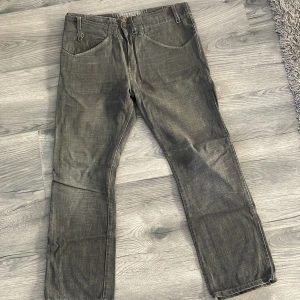 Grå jeansbyxor från Levi's - Säljer ett par grå jeansbyxor från Levi's med klassiska fem fickor och raka ben. Byxorna har synliga sömmar och knappgylf. Passar perfekt till dig som gillar en enkel och stilren look.
