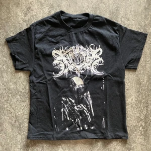 Svart band-tshirt med Xasthur tryck - Cool svart t-shirt med stort vitt tryck framtill i metalstil. Klassisk passform med rund hals och korta ärmar. Perfekt för dig som gillar bandmerch och vill sticka ut.