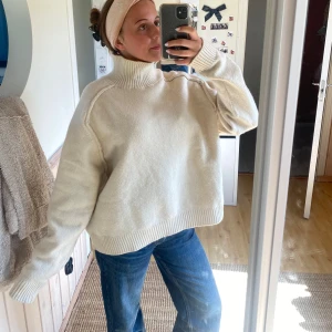 Vit stickad polotröja - Säljer en oversized vit stickad polotröja med hög krage. Tröjan har långa ärmar och breda ribbade muddar vid ärmslut och nederkant. Perfekt för lager-på-lager och supermysig till jeans.