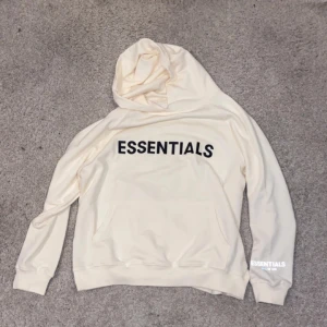 Essentials Hoodie - Tunn skön hoodie nu till sommaren, endast använd några gånger. Loggan på ärmen är en reflex (bilden). Modellen är 177, tröjan sitter ganska löst, strl S.