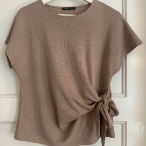 Beige topp med knyt från Zara - Populär tröja från Zara, använd 2 gånger så i nyskick. Skriv om du har fler frågor 💗