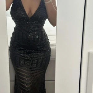 Svart glittrig klänning  - Säljer en svart långklänning med glittriga paljetter och djup v-ringning. Klänningen har en tight passform och en snygg öppen rygg, perfekt för festliga tillfällen eller balen.  Den skulle passa någon med xs/s/m. Lånade bilder men skriv om ni vill ha egna bilder❤️