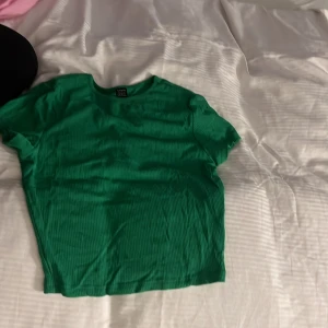 Grön ribbad t-shirt från SHEIN - Säljer en grön ribbad t-shirt från SHEIN i storlek S (EU 36). T-shirten har korta ärmar och en klassisk rund halsringning. Perfekt för dig som gillar färg och enkel stil.