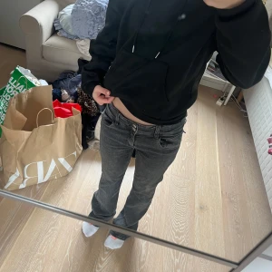 Gina Jeans  - Säljer ett par grå jeans med bootcut passform och låg midja. Byxorna har två stora fickor med lock bak och klassisk femficksdesign fram. Perfekta för en avslappnad och trendig look.