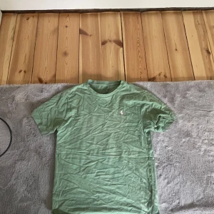 Grön t-shirt från Polo Ralph Lauren - Säljer en grön t-shirt från Polo Ralph Lauren med klassisk passform och liten broderad logga på bröstet. Perfekt basic-plagg med rund hals och korta ärmar. Skön och mjuk bomullskvalitet.