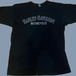Baggy drainer Harley Davidson tröja - Jag är 160cm för referens på bilderna!           Säljer en svart vintage XL baggy drainer Harley-Davidson t-shirt i bra skick med tryck fram och bak. Framsidan har texten 'Harley-Davidson Motorcycles' och baksidan visar en örn med texten 'Pomona Valley Montclair, CA'.  100% bomull Mått finns på andra bilden Priset är diskuterbart, men först till kvarn gäller! Skickar så snabbt som möjligt