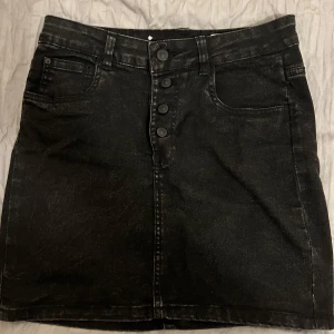 Svart regular waist minikjol  - Säljer en regular waist svart jeanskjol i nyskick. Den är i storlek 36. Perfekt plagg till sommaren, både snygg och lätt att matcha!