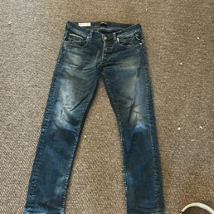 Replay jeans  - Snygga Replay Grover jeans i blå tvätt med coola slitningar och klassiska fem fickor. Jeansen har raka ben och normal passform, med Replay-logga på bakfickan och läderpatch i midjan. Perfekt för dig som gillar en avslappnad och stilren look.