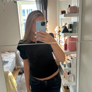 Svart puffärm topp med rund hals - Säljer en svart topp med puffiga korta ärmar och rund hals. Modellen är figurnära och har en enkel, stilren look som funkar till jeans eller kjol. Materialet känns mjukt och stretchigt, perfekt för dig som gillar bekväma men snygga plagg. Köpt på hm för 150. Säljer för 110. Pris går att diskutera. Skriv till mig vid frågor🫶 nästan aldrig använd