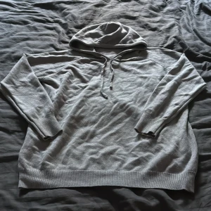 Hoodie  - Säljer en stilren ljusgrå hoodie med huva och snörning framtill. Tröjan har långa ärmar och ribbade muddar vid ärmslut och nederkant. Perfekt för chill dagar och enkel att matcha med jeans eller joggers.