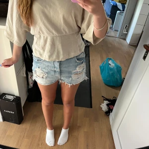 Ljusa jeansshorts  - Säljer ett par ljusblå, högmidjade jeansshorts från Bershka. De har slitna detaljer, fransig kant och klassisk femficksdesign. De är i storlek 40