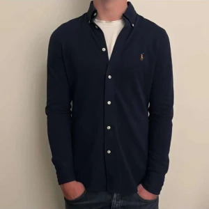 Mörkblå skjorta från Ralph Lauren - Snygg mörkblå skjorta från Ralph Lauren med klassisk button-down krage. Skjortan är långärmad och har en normal passform, perfekt till jeans och t-shirt under. Den är i 10/10 skick och knappt använd. Den är i M men passar S. Skriv vid frågor eller funderingar!😊