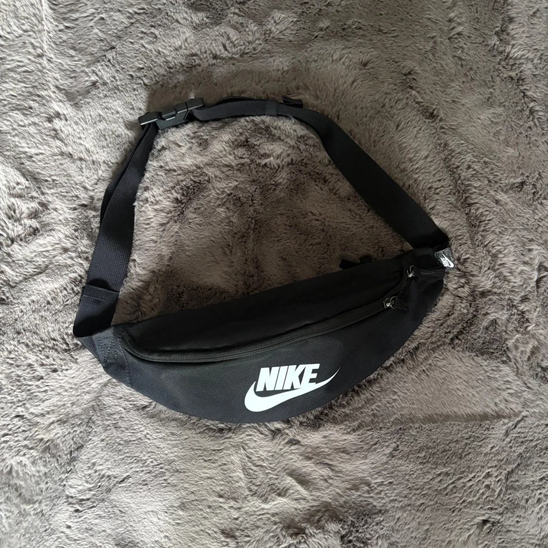 Svart Nike axelväska med logga och tunn träningsjacka. - 1