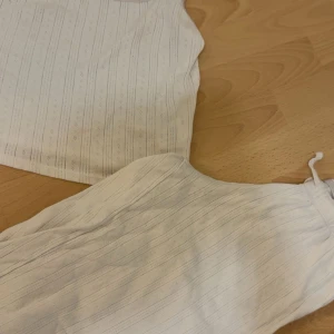 Vit randig pyjamas sätt - Supersöt vitt pyjamas sätt från lager 157 i storlek XS. Toppen har tunna axelband med spetskant och ett diskret randigt mönster med små hålbroderier. Perfekt för varma dagar och chill vibes. Materialet är mjukt och känns skönt mot huden.