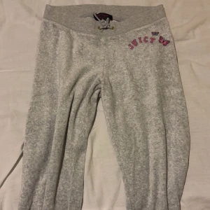 Grå mjukisbyxor Juicy Couture - Säljer ett par grå mjukisbyxor från Juicy Couture med snörning i midjan och rosa JUICY-text samt fjärilar broderade vid höften. Byxorna har en loose passform och är perfekta för chill dagar. Supermjukt material som känns skönt mot huden.