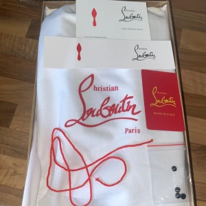 Christian Louboutin svarta sneakers med nitar - Svarta sneakers från Christian Louboutin med coola svarta nitar på tån. Skorna har snörning och är gjorda i mocka med en rund tå och platt sula. Insidan är beige och de kommer med originalförpackning och extra knappar, den kommer också med ett kort som bevisar att det är äkta. Köper du så kan du också få en liten röd skohorn som inte är kopplat till louboutins, pris kan såklart diskuteras o sänkas ( har tillfälligt lagt in andra snören byter tillbaka när du har köpt)
