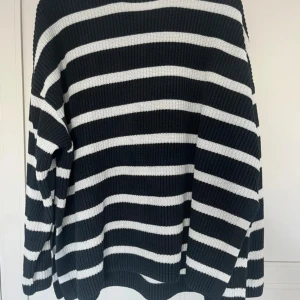 Svartvit randig stickad tröja H&M - Säljer en svart och vit randig stickad tröja från H&M i storlek M. Tröjan har breda horisontella ränder, ribbad struktur och långärmade ärmar. Perfekt för dig som gillar en chill och stilren look med lite oversized känsla.
