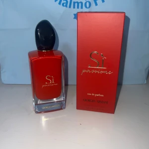 Giorgio Armani Sì Passione EdP 100ml - Säljer en lyxig parfymflaska Sì Passione från Giorgio Armani, 100 ml eau de parfum. Flaskan är elegant röd med svart kork och har en stilren, fyrkantig form i glas. Kommer med matchande röd kartong med gulddetaljer. Perfekt för dig som gillar exklusiva dofter.
