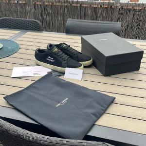 Svarta Saint Laurent sneakers strl 43 - Säljer nu mina svarta saint Laurent skor, de är i riktigt fint skick och de är aldrig använda endast testade. Skorna är storlek 43 men passar även 42, de är riktigt bekväma och allt som syns i bilden medföljs! Säljes nu eftersom de aldrig används samt inte passar mig, om ni har frågor eller liknande är de bara att skriva privat😀