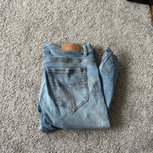 Blå jeans från Tiger of Sweden - Snygga blå jeans från Tiger of Sweden i modellen Leon. De har klassisk femficksdesign, raka ben och twillvävt jeanstyg. Passar dig som gillar stilrena och tidlösa jeans med en modern touch. Perfekt för dig som vill ha ett par jeans med bra passform och cool tvätt.