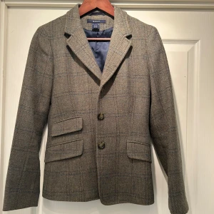 Damkavaj GANT i ull - Ursnygg ull-kavaj från Gant, mossgrön med mörkblå rutor, dubbelficka på ena sidan, slits baktill, lätt figursydd. Mycket bra skick. 4500 nypris.