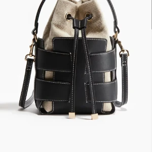 Svart och beige axelväska med snörning - Snygg axelväska i svart skinn med beige tyginsida och cool snörning upptill. Väskan har ett unikt rutmönster av skinnremmar och guldfärgade metalldetaljer. Perfekt för dig som vill ha en trendig och praktisk väska med lite edge. Väskan finns inte att köpa längre och är väldigt efter frågad. Hör av dig vid intresse eller frågor❤️