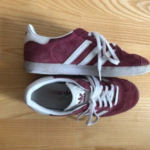 Adidas Gazelle - Säljer ett par vinröda Adidas Gazelle sneakers i storlek 39. De är använda men i bra skick, har smuts på sulor och skosnören. Nypris 1 349kr