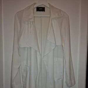 Vit trenchcoat från Bik Bok - Säljer en stilren vit kappa från Bikbok i mycket bra skick. Den har en elegant design med långa ärmar och en fin krage. Perfekt för vår och höst när du vill se chic ut.🕊️