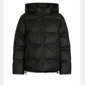 Svart pufferjacka med huva - Nypris 1799:- !!!Säljer en svart pufferjacka med huva och dragkedja framtill. Jackan har en clean look, breda kanaler och två sidofickor. Perfekt för dig som vill ha en varm och stilren jacka till vintern. Passformen är normal och materialet är syntet. endast använd en vinter! Väldigt varm med teddy fickor inuti. Väldigt populär och ofta slutsåld. Storlek 34 passar S