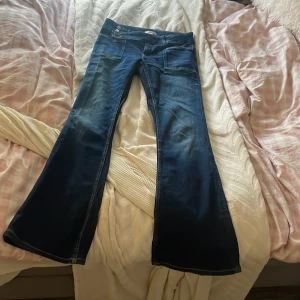 Blå bootcut jeans från Gina Tricot/ jeansy z niskim stanem gina tricot - Snygga blå jeans från Gina Tricot i storlek 170 med bootcut passform och låg midja. Jeansen har framfickor med markerade sömmar och två knappar i midjan för mindre midjor/höfter. Materialet är klassiskt jeans med en mörk tvätt och lätt slitning för cool vibe. Helt oanvända. Orginalpris 450kr. Pris kan förhandlas