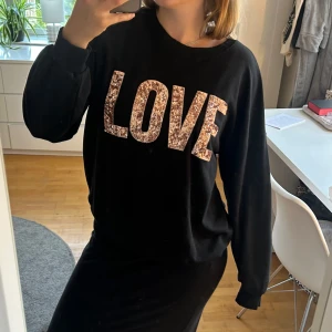 Sweatshirt - Säljer en svart charmig sweatshirt med glittrande paljetttexten 'LOVE' på framsidan! Perfekt för att ge lite extra bling! Säljer den pågrund av förlite användning. Skicket är jättebra och den är knappt använd! Den är i storlek S men den passar definitivt storlek M också. Skriv om du har frågor eller undrar något!💖