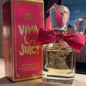 Juicy Couture Viva La Juicy parfym 50ml - Juicy Couture Viva La Juicy Eau de Parfum 50ml. Flaskan är fyrkantig med en stor, kristalliknande kork och dekorerad med en rosa rosett samt guldfärgade hängen. Doften är söt och stilren ✨ Knappt använd vara uppackad och testad. 