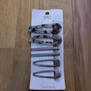 Set med hårspännen i silver och marmor - Snyggt set med sex hårspännen, två i marmorliknande mönster med mix av grått, vitt och beige, samt fyra i blankt silver. Perfekt för att fixa frisyren och ge en cool touch till din look. Spännena har olika former, både klassiska och moderna. Hårspännen i marmor har lite rost under men inget som syns på