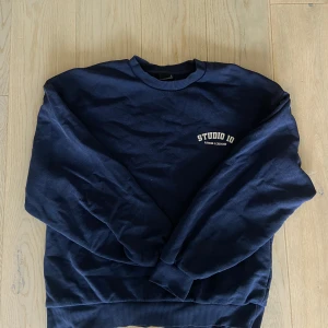 Mörkblå sweatshirt från Gina Tricot - Säljer en mörkblå sweatshirt från Gina Tricot med trycket 'STUDIO 10 FITNESS & EXERCISE' på bröstet. Tröjan har rund hals, ribbade muddar och är tillverkad i mjuk bomull. Perfekt för chill eller träning, enkel och stilren design. Perfekt coverup på gymmet💙