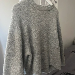 Grå stickad tröja från 157 XS - Mysig grå stickad tröja från 157 i storlek XS. Tröjan har en rundad hals med ribbad kant och långa ärmar. 