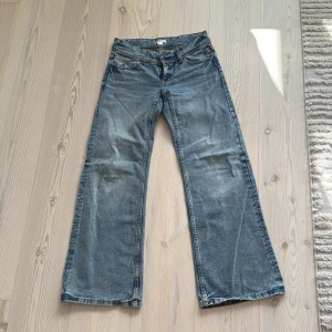 Wide jeans från Gina Tricot, ljusblå - Snygga ljusblå jeans från Gina Tricot i wide modell med låg midja. Klassisk femficksdesign, coola detaljer på bakfickorna med knapp och slitningar för en avslappnad vibe. Perfekta för dig som gillar retro och streetstyle. Materialet är jeans med kontrastsömmar.