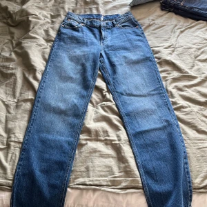 Blå raka jeans från Bubbleroom - Säljer ett par klassiska blå jeans från Bubbleroom med rak passform och normal midja. Jeansen har fem fickor, bälteshällor och är tillverkade i slitstarkt denim. Perfekta för dig som gillar en enkel och tidlös stil.