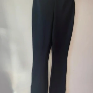 Svarta bootcut byxor från H&M XS - Snygga svarta bootcut byxor från H&M i storlek XS. Byxorna har en klassisk siluett med utsvängda ben och är tillverkade i ett mjukt syntetmaterial som ger en skön passform. Perfekta för dig som gillar stilrena och trendiga plagg.