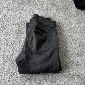 Svarta jeans tiger of Sweden 28/32 - Svarta jeans från tiger of Sweden i modellen 'Darkene', storlek 28/32. Snyggt smal passform med klassisk femficksdesign och svarta sömmar. Perfekt för dig som gillar stilrena och enkla jeans med modern look.