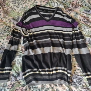 Randig stickad tröja i svart och lila - Är egentligen storlek XL. Sitter perfekt oversized på mig som bär storlek S och snyggt och löst på bekant som bär M-L